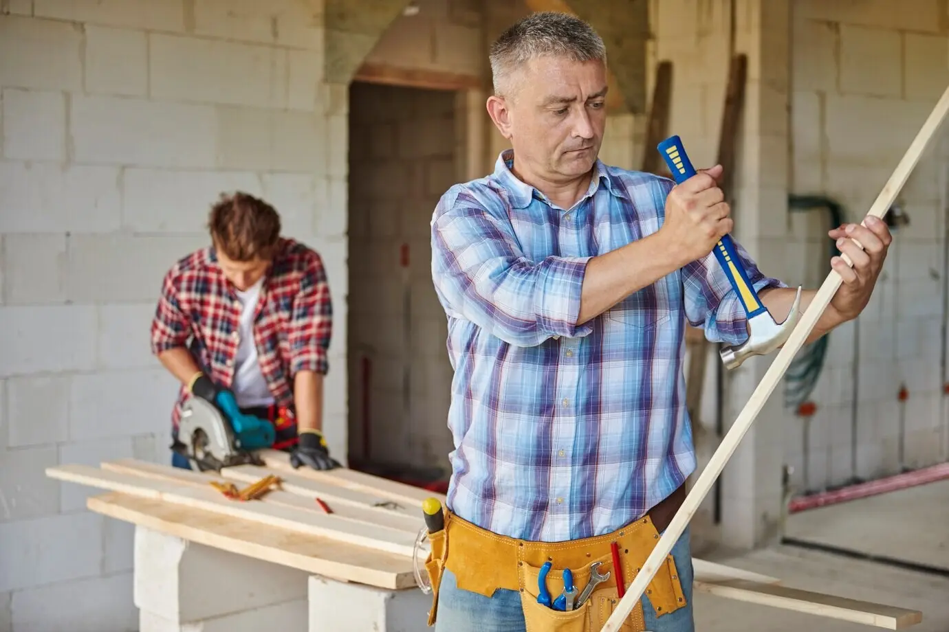 A motivated carpenter using a hammer in the foreground.